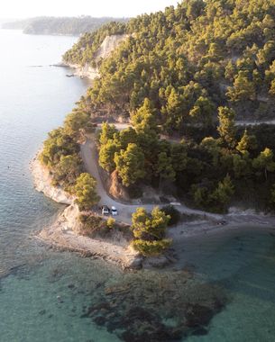 An aerial view of a wooded peninsula and turquoise water