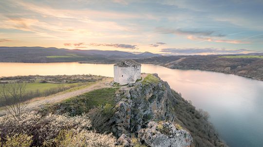 A small tower on a cliff above a bay at dusk
