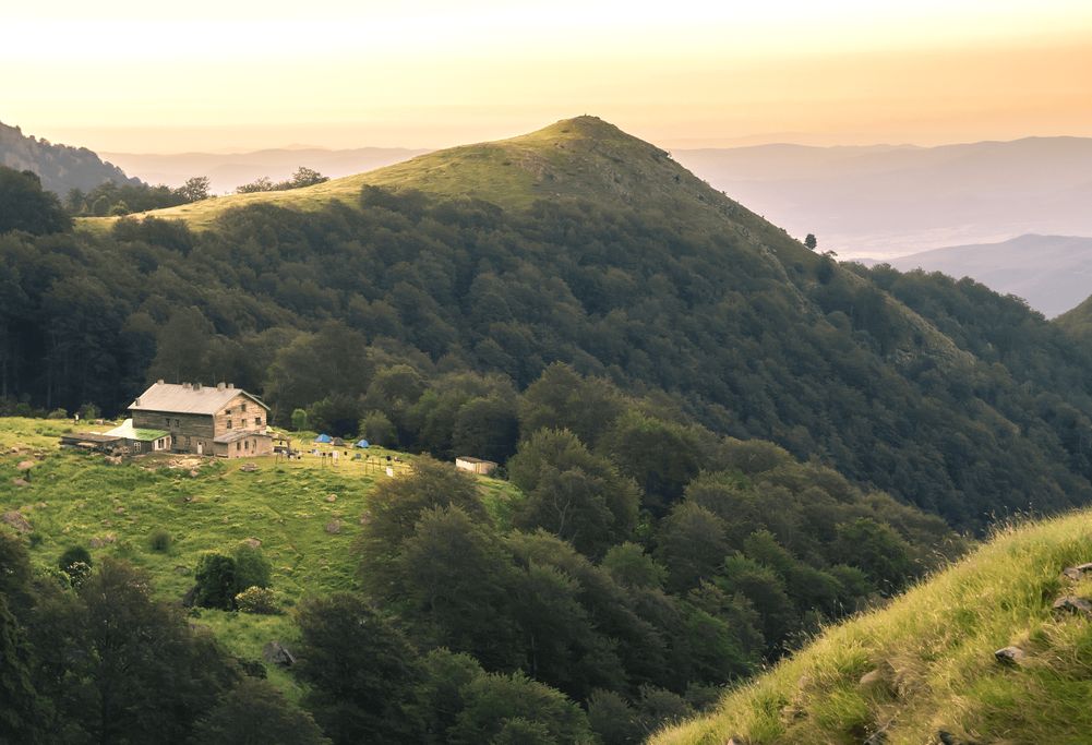 Green hills with a farmhouse at sunset
